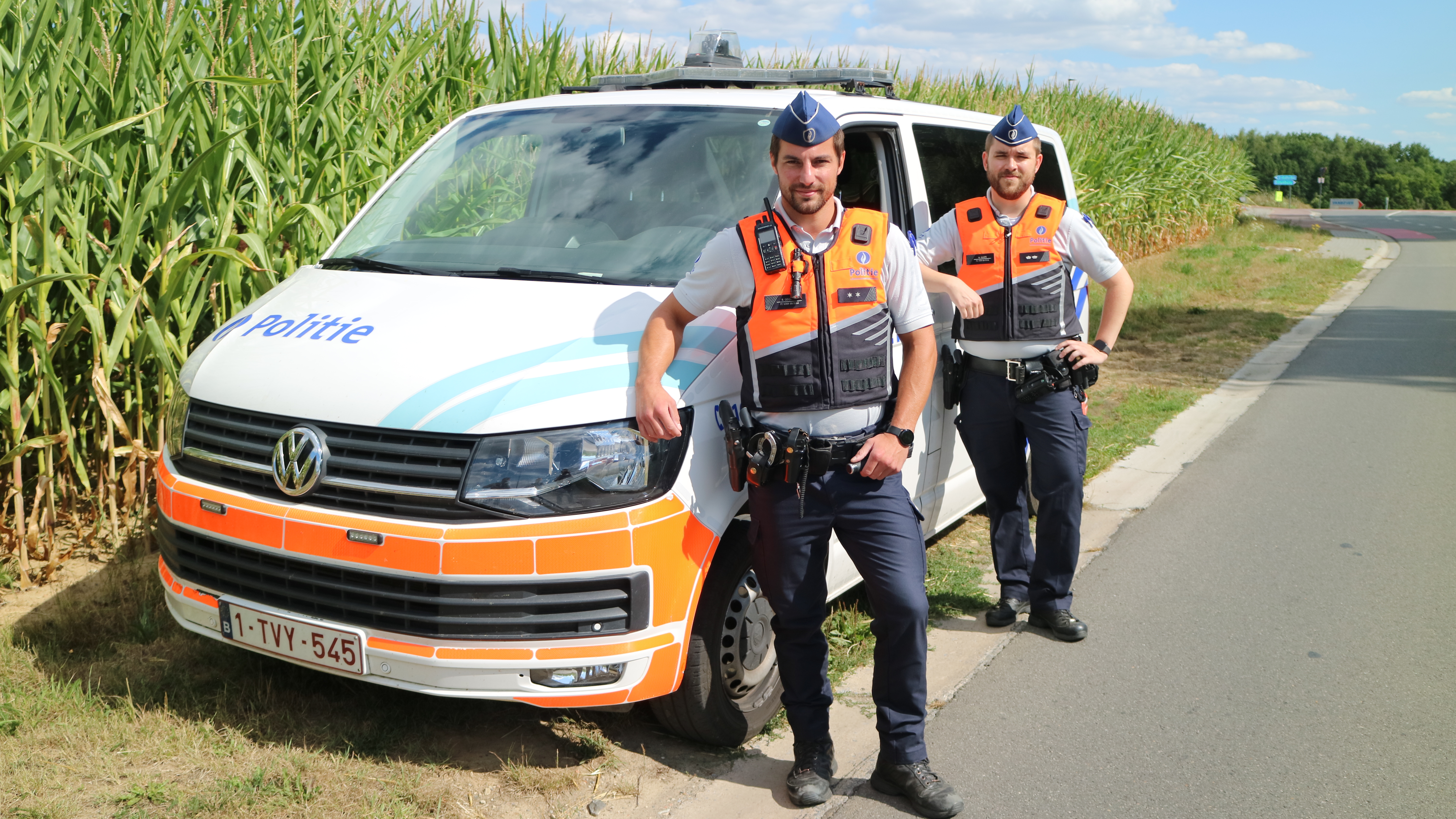 Twee politiemannen bij hun dienstvoertuig